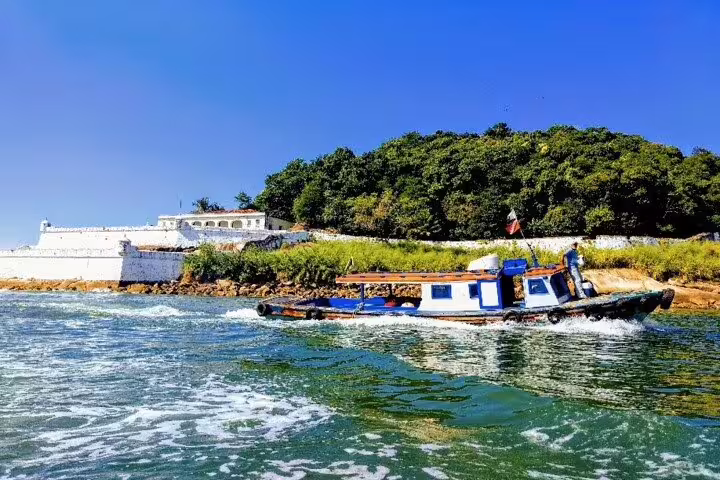 Scenic private boat tour in Santos with a historic fort and lush greenery under a clear blue sky.