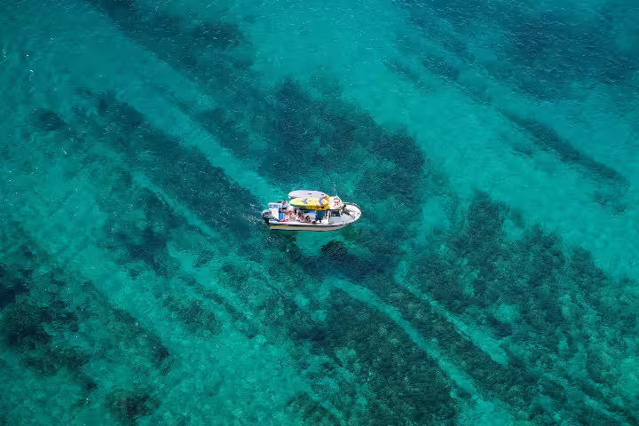 Aerial view of a private boat tour in Sesimbra, gliding over the crystal-clear waters of Arrábida Natural Park.