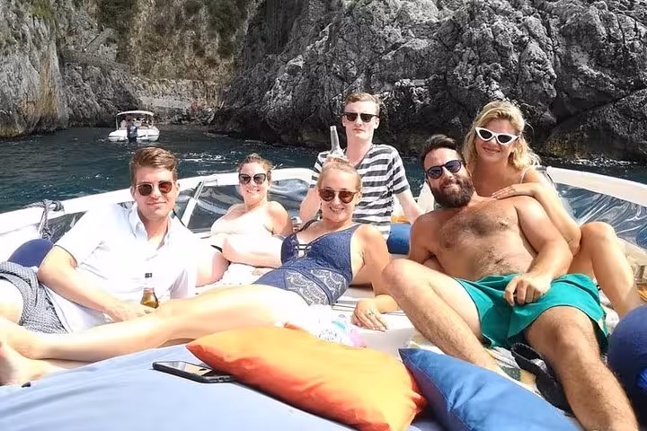 Group relaxing on a private boat tour from Sorrento to Amalfi, enjoying stunning coastal views and sunshine.