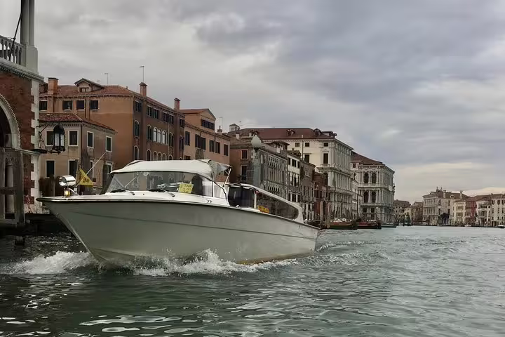 Elegant private boat cruising along Venice's Grand Canal with historic buildings in the background.