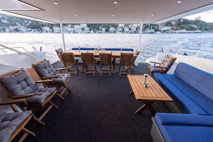 Spacious private Bosphorus yacht deck in Istanbul with lounge seating and dining table overlooking shoreline