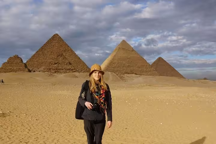 Traveler posing in the Giza desert with pyramids on a private Cairo day trip from Soma Bay, Makadi Bay and Hurghada