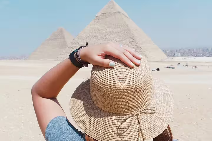 Traveler in sun hat overlooking the Giza Pyramids, private Cairo tour combining NEMC, Egyptian Museum and pyramids