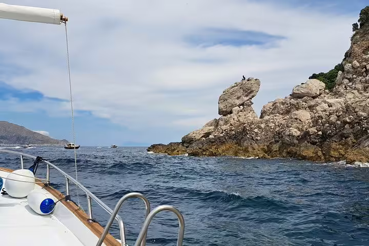 Private Capri boat tour cruising past rugged sea cliffs and rocks, with open Mediterranean views in 2 hours