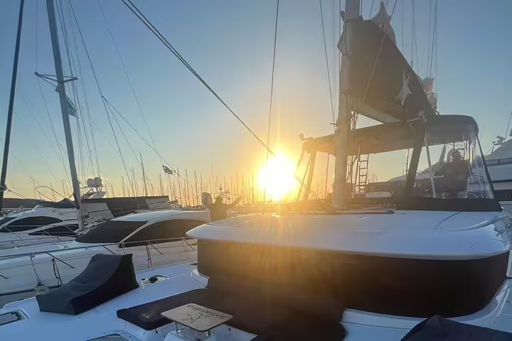 Experience a stunning sunset on a private catamaran cruise in Santorini's picturesque harbor.