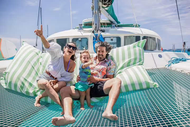 Family enjoying a sunny day on a private catamaran trip between Ibiza and Formentera, relaxing on deck with ocean views.