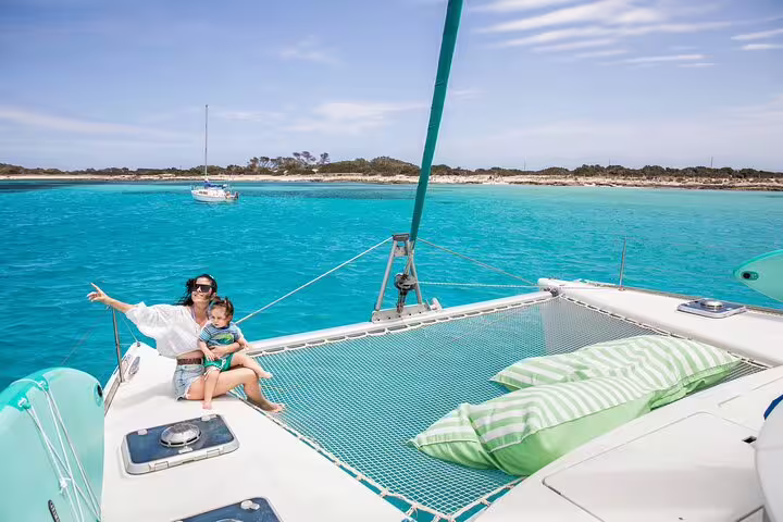 Family enjoying sunny day on a private catamaran in turquoise waters of Ibiza and Formentera full-day sailing tour.