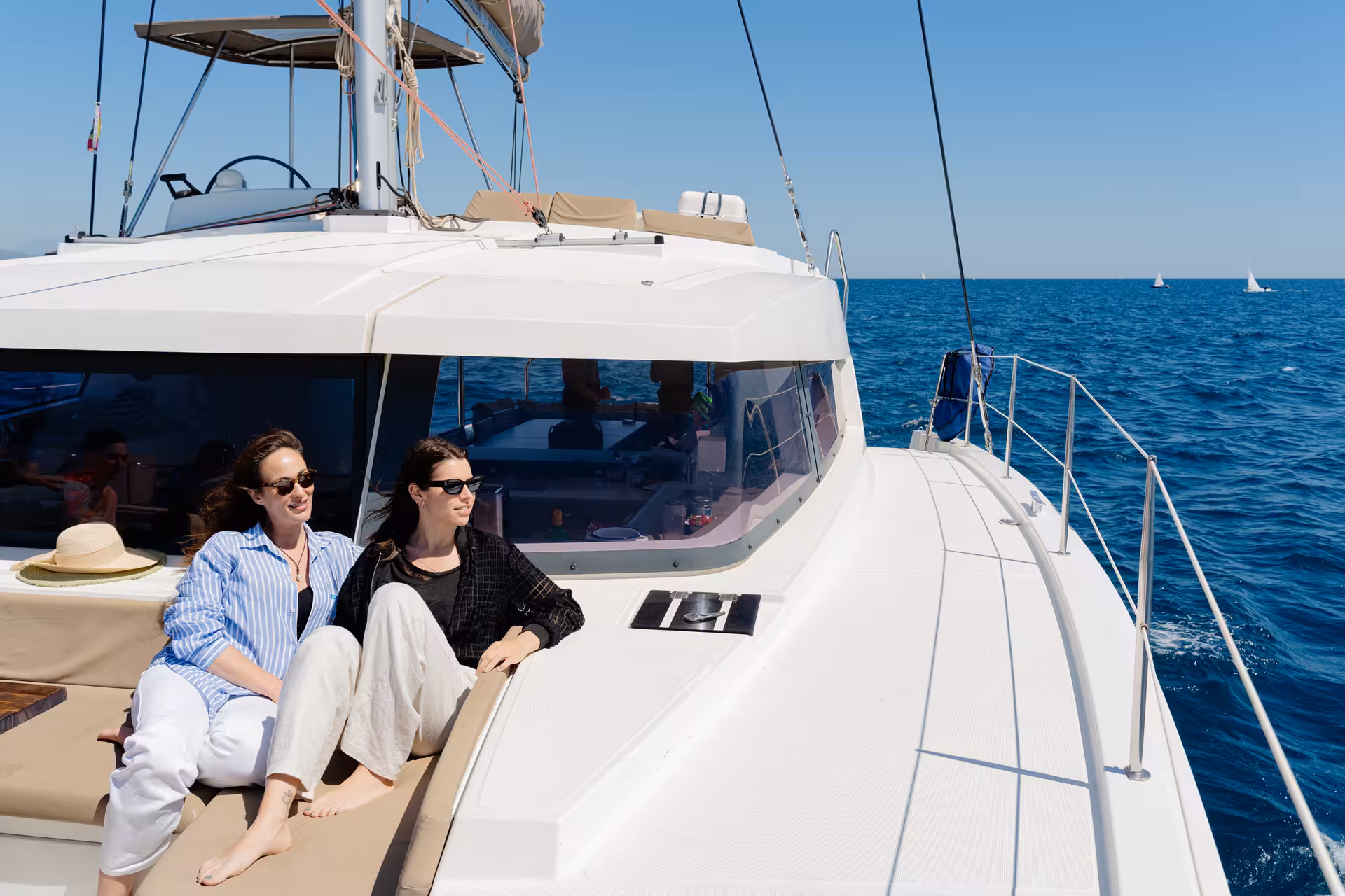 Guests relaxing on the deck of a private catamaran rental, sailing on calm blue water with ocean views