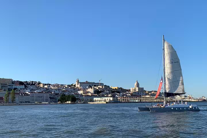 Catamaran sailing along Lisbon's scenic waterfront with iconic cityscape views on a private group tour.