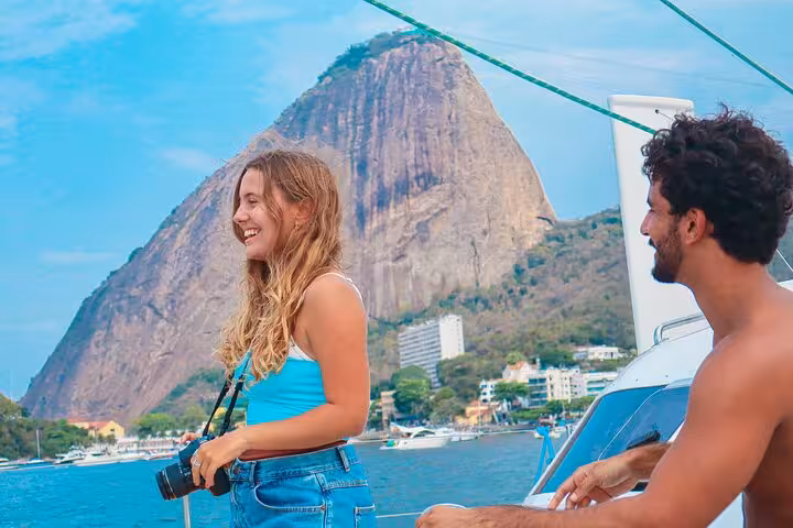 Guests enjoying a private catamaran tour in Rio with open bar and BBQ, sailing past Sugarloaf Mountain