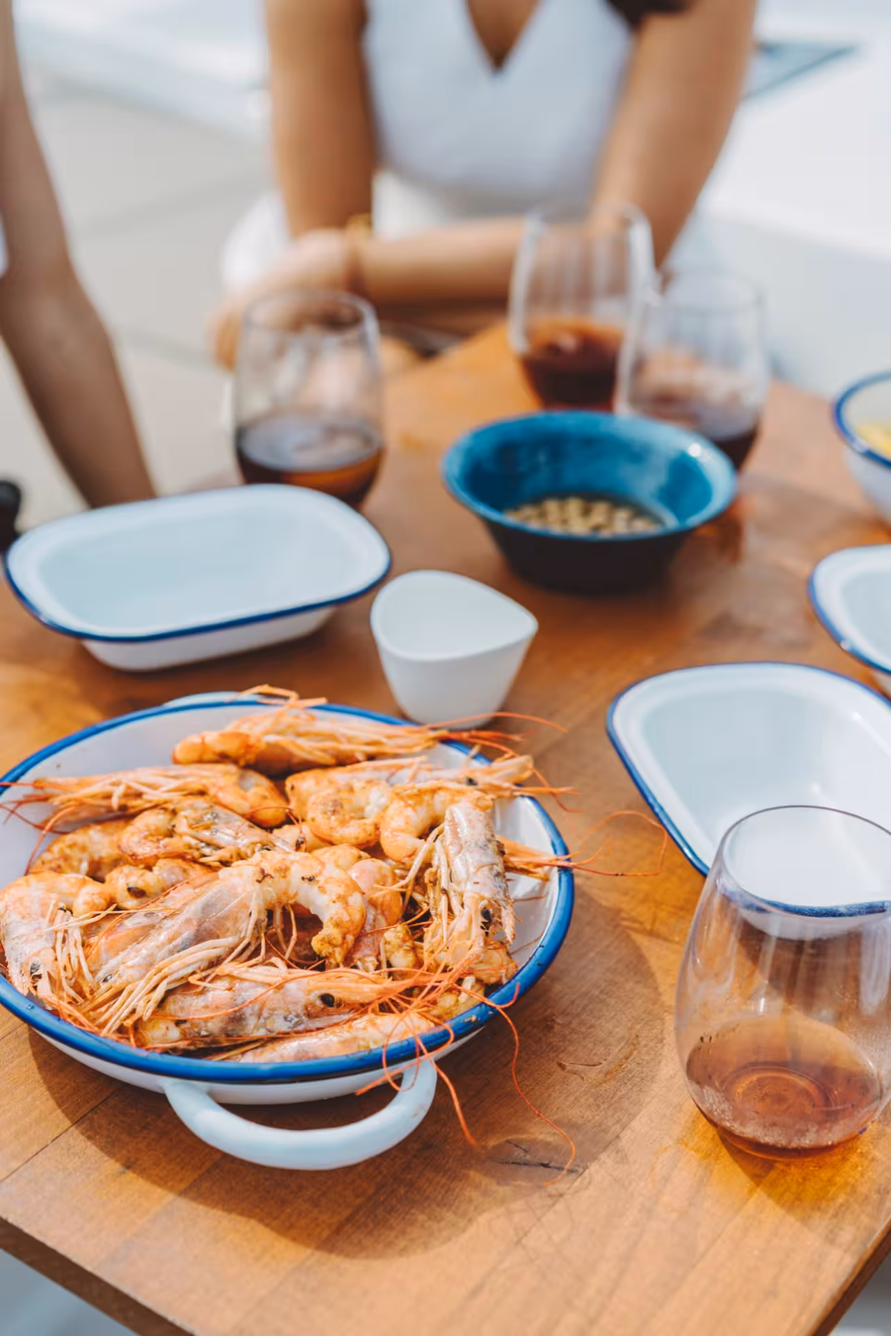 Seafood dinner by a private chef with grilled prawns and wine on a patio table, intimate chef-at-home experience