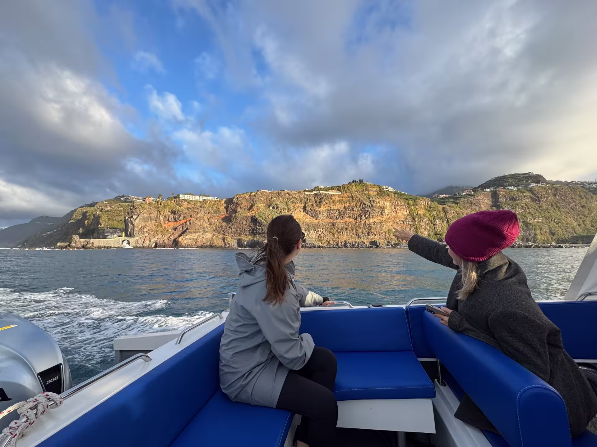 Two passengers on a private cruise admiring stunning coastal cliffs, perfect for an afternoon tea experience.