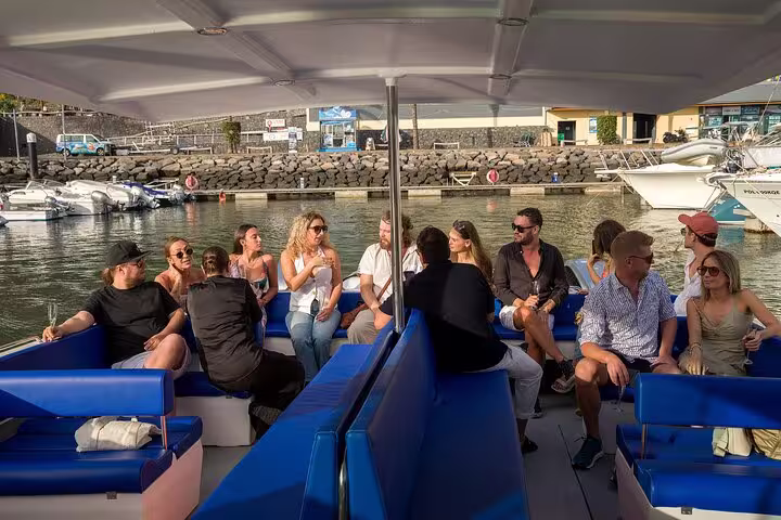 Group enjoying afternoon tea and coffee on a private cruise with scenic marina views in the background.