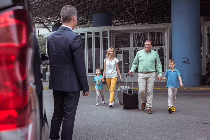 Family arriving with luggage, greeted by a driver for their private day trip to Tivoli from Rome.