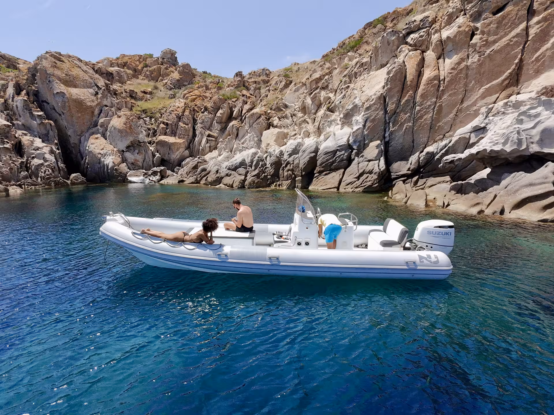 Private dinghy anchored near rocky cliffs on Costa Rei's stunning coastline, ideal for a serene Sardinian adventure.