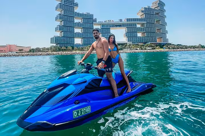 Two people on a jet ski in Dubai with a striking hotel backdrop, ideal for a private photoshoot adventure.