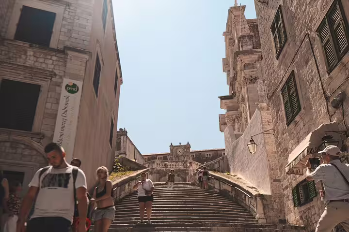 Tourists climbing Dubrovnik Old Town stone steps toward historic landmarks on a private Dubrovnik tour