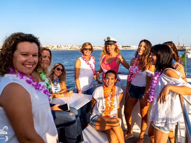 Smiling women wearing leis enjoying a lively boat party under the sun on a private event cruise.