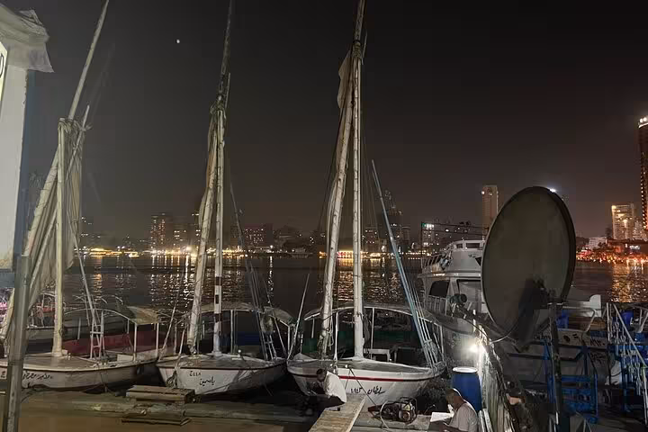Traditional felucca sailboats docked on the Nile at night in Cairo, ideal for a private felucca boat ride and city lights