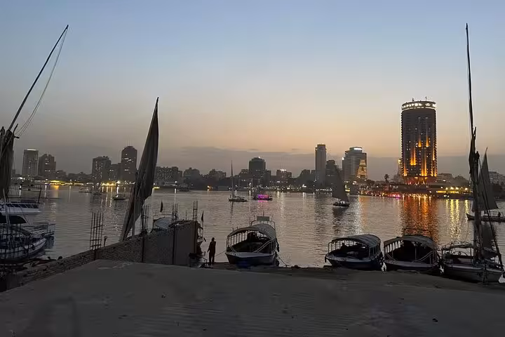 Sunset view of Cairo skyline from the Nile on a private felucca boat ride with traditional sails and moored boats