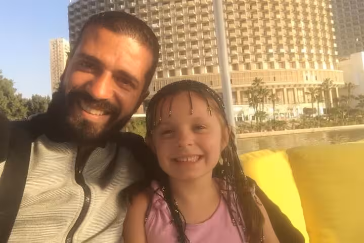 Smiling guests on a private felucca boat ride on the Nile in Cairo with city skyline behind