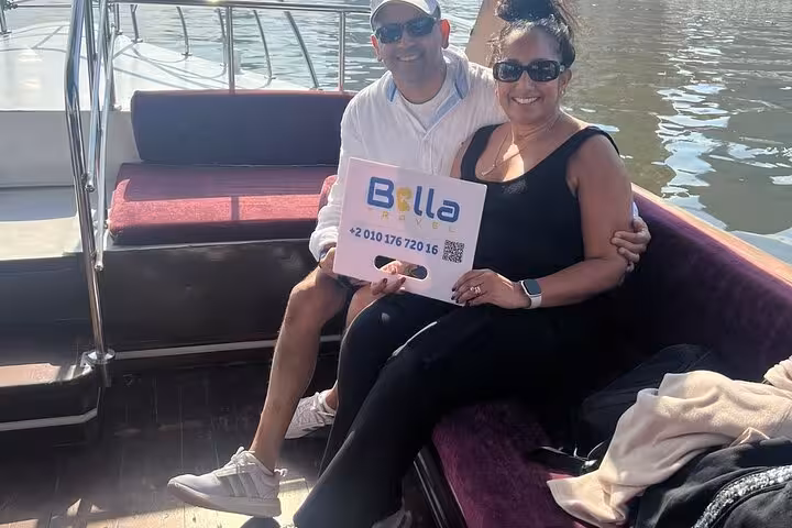 Happy couple on a private Nile boat in Luxor holding tour sign, private felucca trip and transfer service