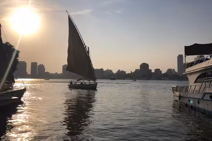 Private felucca boat ride on the Nile in Cairo at golden hour, sailing past the waterfront skyline