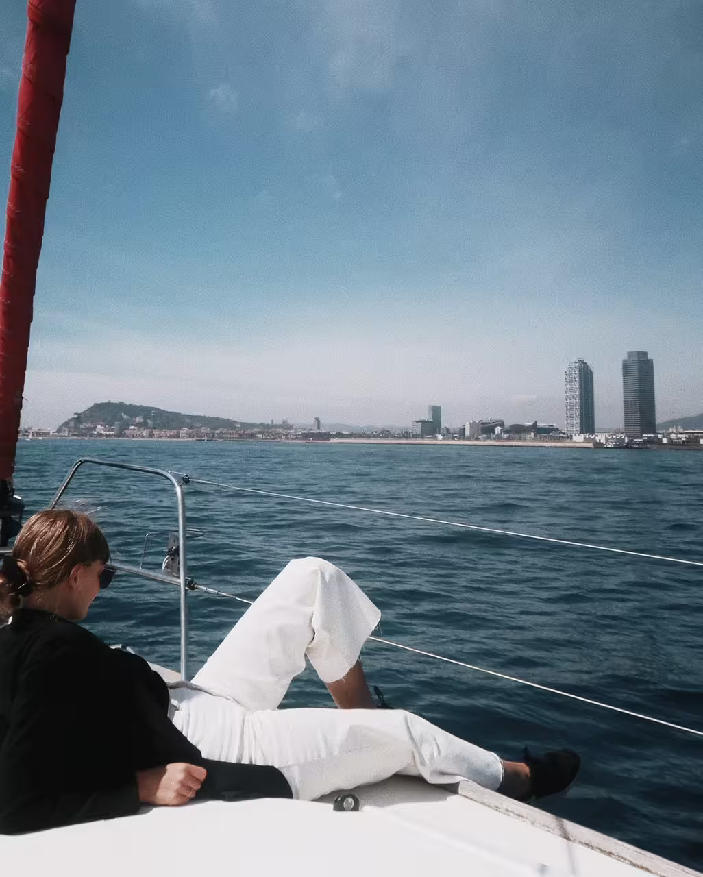 Relaxing on a sailboat with panoramic views of Barcelona's skyline during a private full-day sailing experience.