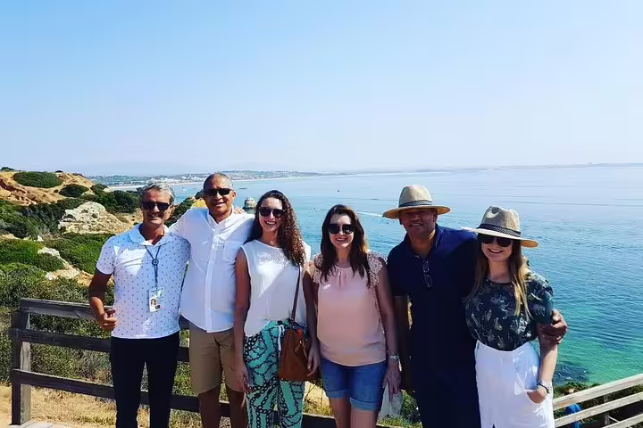 Group of tourists enjoying the scenic Algarve coastline on a sunny day during the private tour from Lisbon.