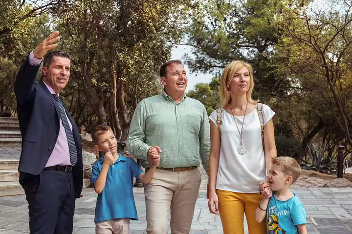 Private half-day Athens sightseeing tour with local guide walking a family through lush city park paths