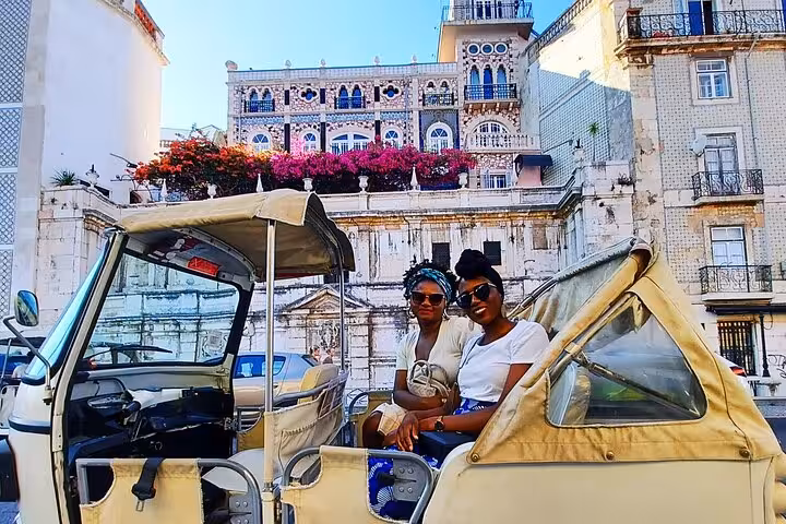 Two guests seated in a tuk tuk near São Jorge Castle on a 2-hour private historic Lisbon tuk tuk tour