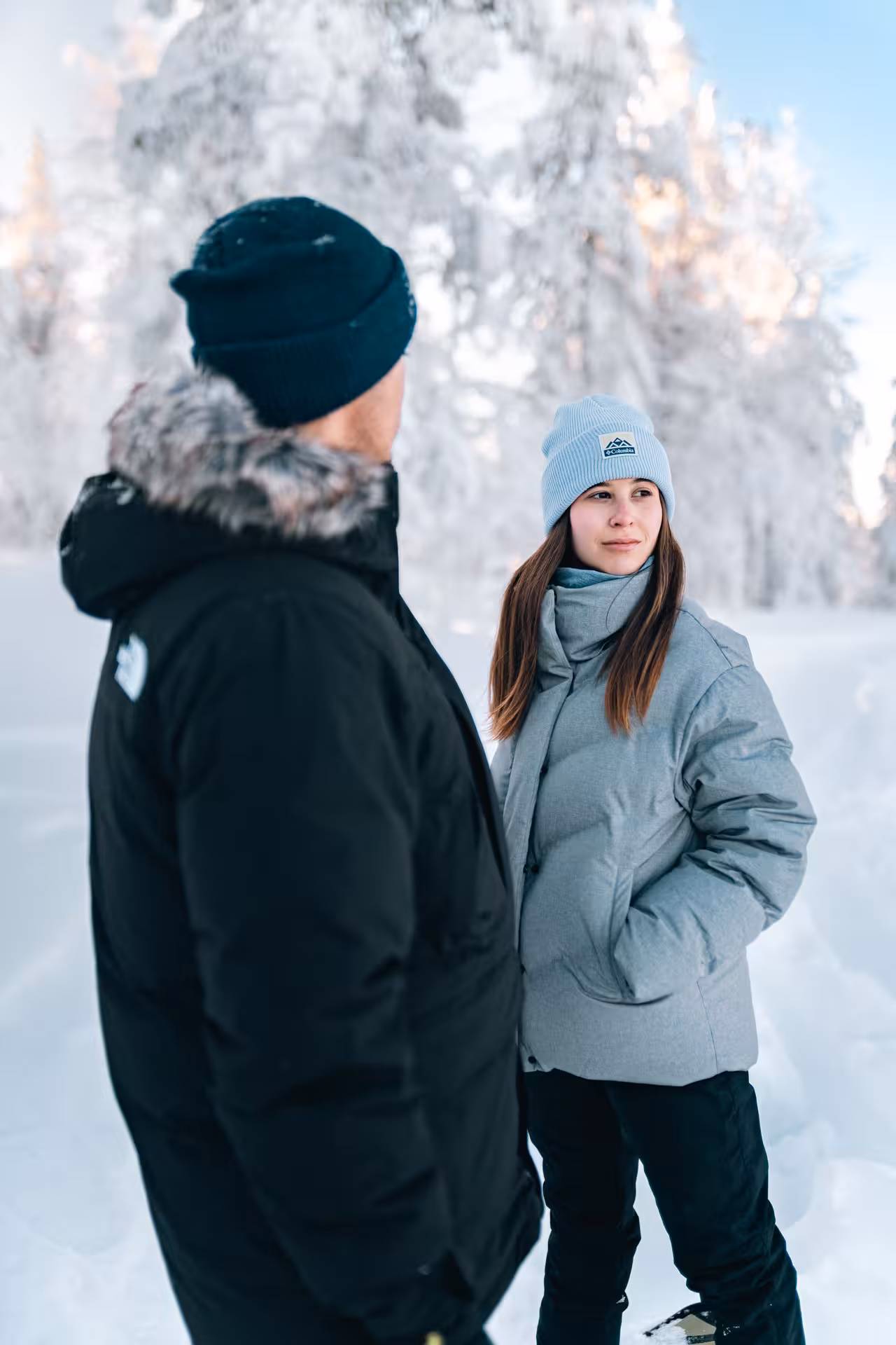 Two people in winter gear standing in a snowy Rovaniemi landscape during a private photo session.