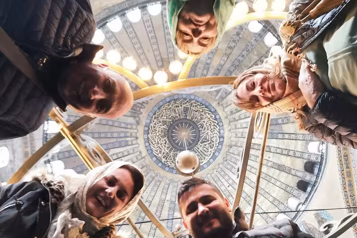 Private Istanbul tour visitors under ornate dome interior, looking up at historic mosque ceiling details