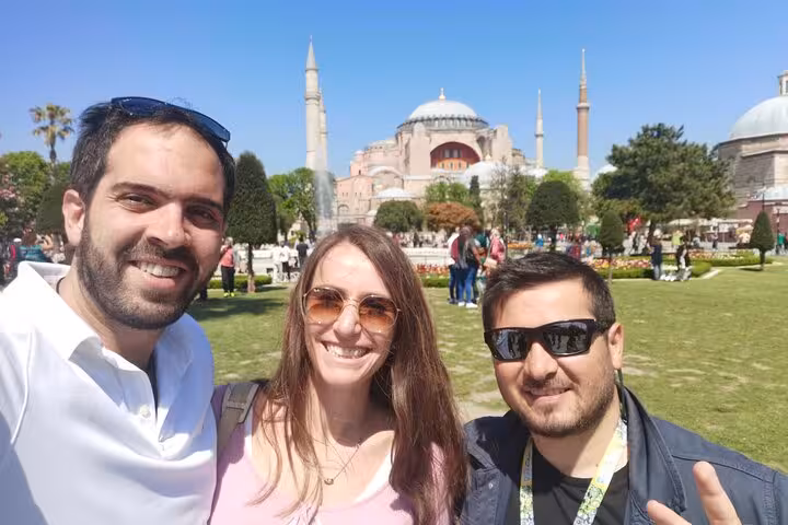 Private Istanbul tour guests smiling in Sultanahmet Park with Hagia Sophia and minarets behind
