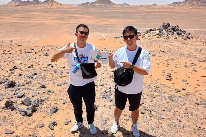 Travelers pose on a private Jeep safari in Egypt’s White Desert near Bahariya Oasis, with rocky dunes behind