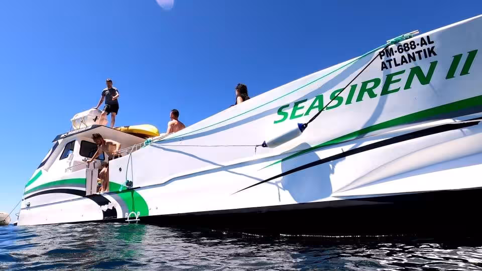 Guests relaxing on the Seasiren II support boat during a private kayak tour, anchored on calm blue ocean under clear Algarve skies