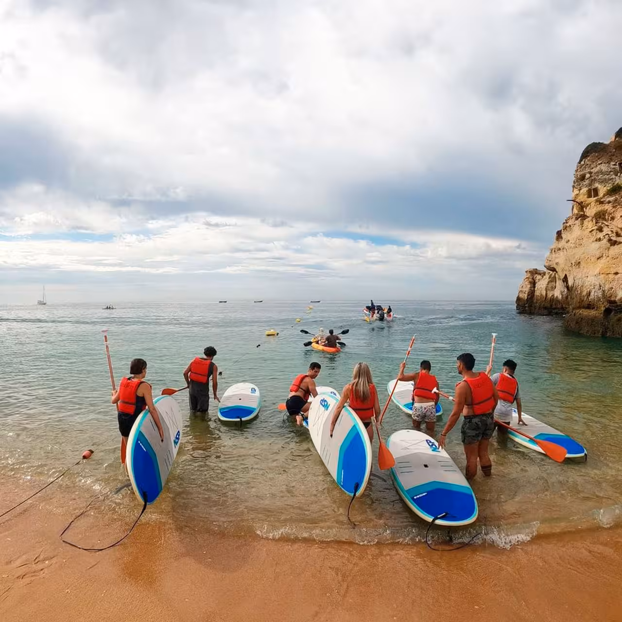 Participants preparing for a stand-up paddleboarding session on a scenic beach with vibrant boards.