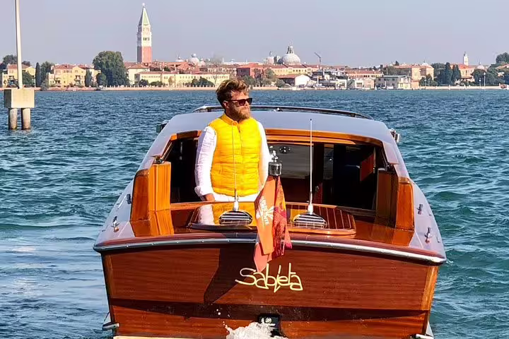 Luxurious private LimoBoat navigating the scenic waterways of Murano with a stylish passenger enjoying the view.