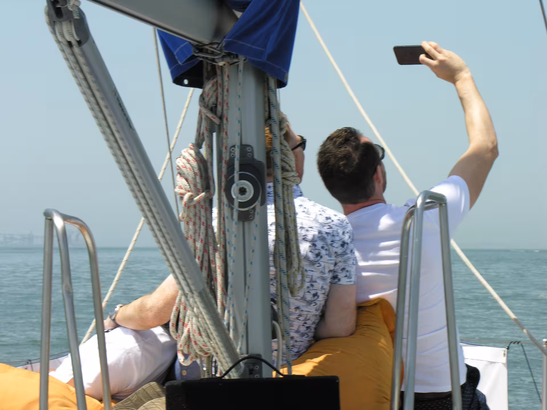 Friends taking a selfie on a private Lisbon sightseeing cruise sailboat on the Tagus River under clear skies