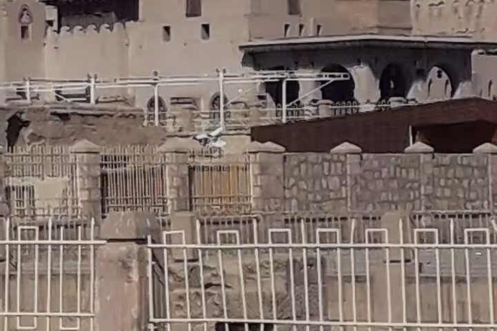 Private Luxor horse carriage tour passing historic stone walls and gated riverside promenade in Luxor City