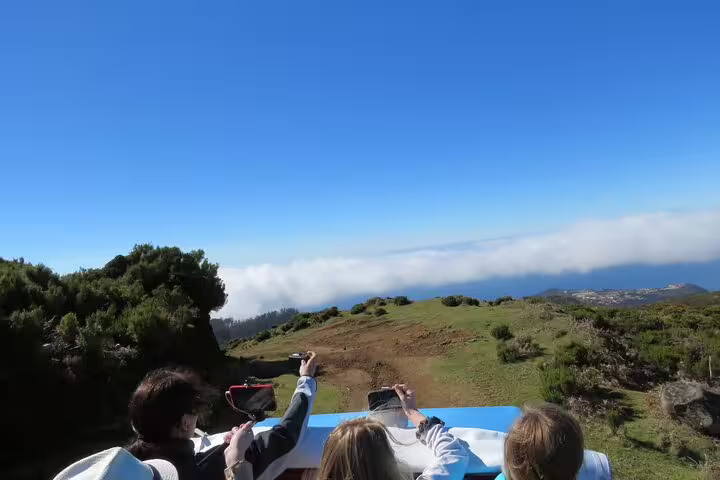 Tourists enjoy panoramic views from a jeep during the Private Magical Shore Excursion West, capturing scenic landscapes and blue skies.