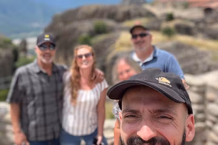 Travelers enjoying a private Meteora day tour from Athens, posing with dramatic rock formations in the background