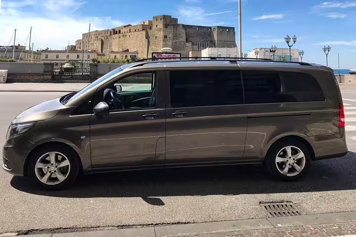 Modern minivan parked by Naples waterfront, spacious vehicle used for private Positano to Rome transfer service