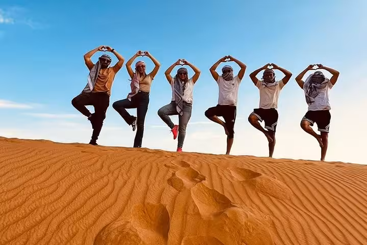 Group posing on golden sand dunes during private morning desert safari, ideal stop before flamingo bird watching