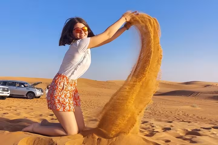 Traveler sandboarding on golden dunes during private morning desert safari, ideal for wildlife and flamingos