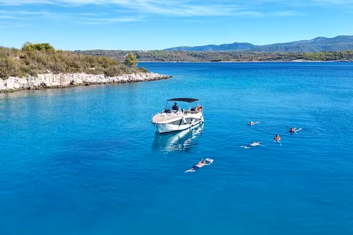 Private motorboat anchored in calm blue Adriatic bay with guests swimming, ideal private boat tour in Croatia