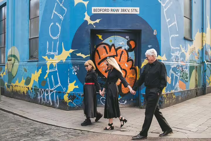 Three people walking past a graffiti-adorned wall in Dublin's Bedford Row during a private photography tour.