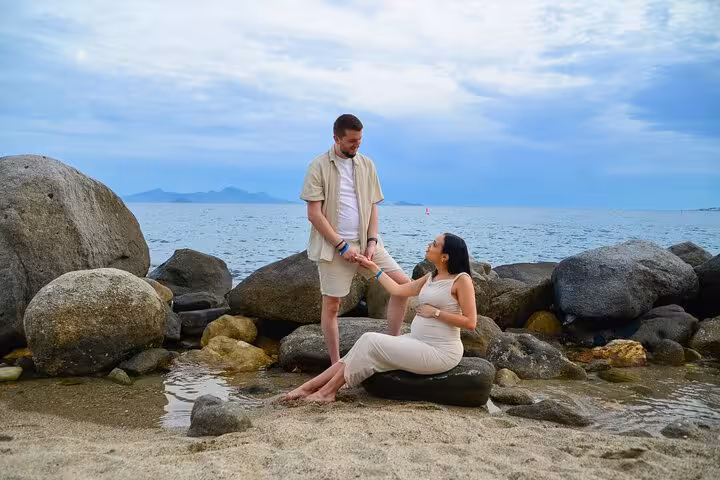 Man helping woman on rocks beside Analipsi sea, highlighting intimate private photoshoot experience.