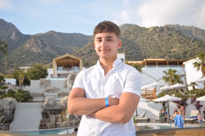 Young man in a white shirt posing confidently with scenic mountain backdrop during a private photoshoot in Malia.