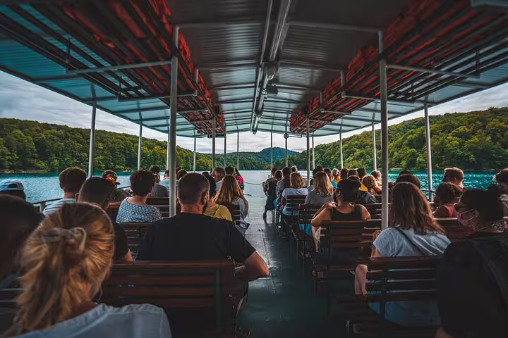 Boat ride across Plitvice Lakes with passengers enjoying scenic views on a Private Plitvice Lakes tour